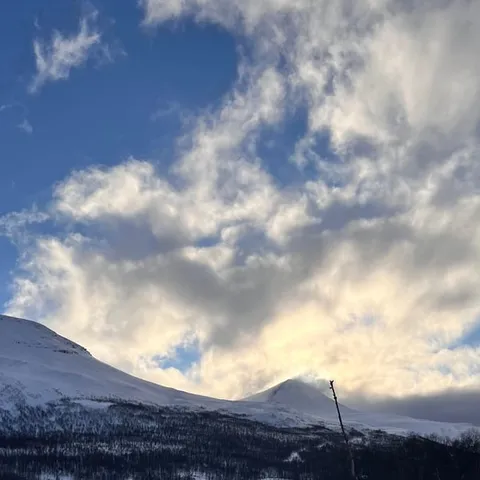 A dog team on the snow below the Tamokdalen mountains