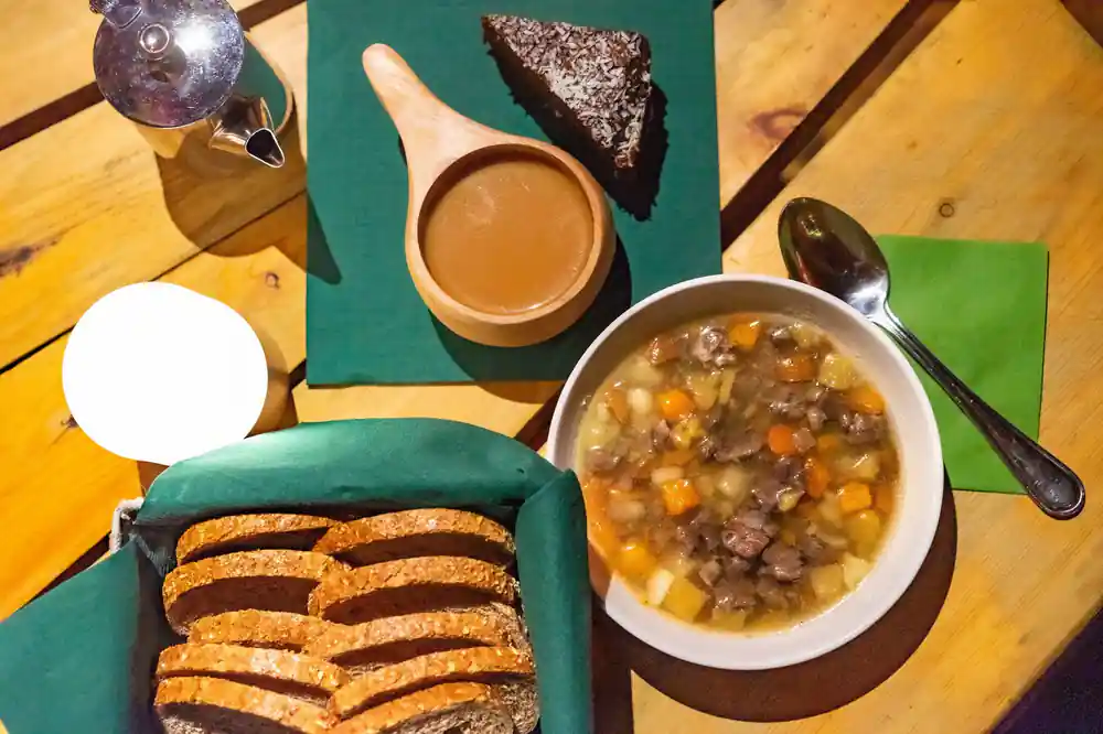 A bowl of Bidos reindeer stew with sliced bread, coffee and chocolate cake