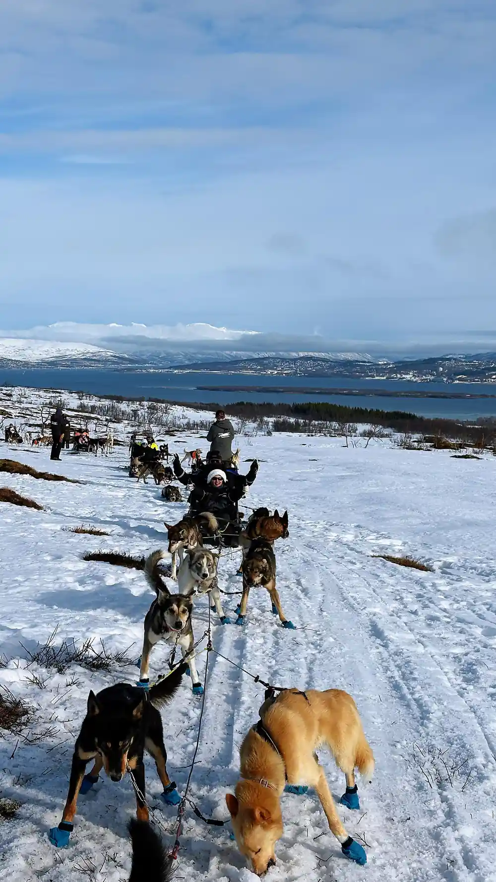 A driver and team setting off with the fjord far below