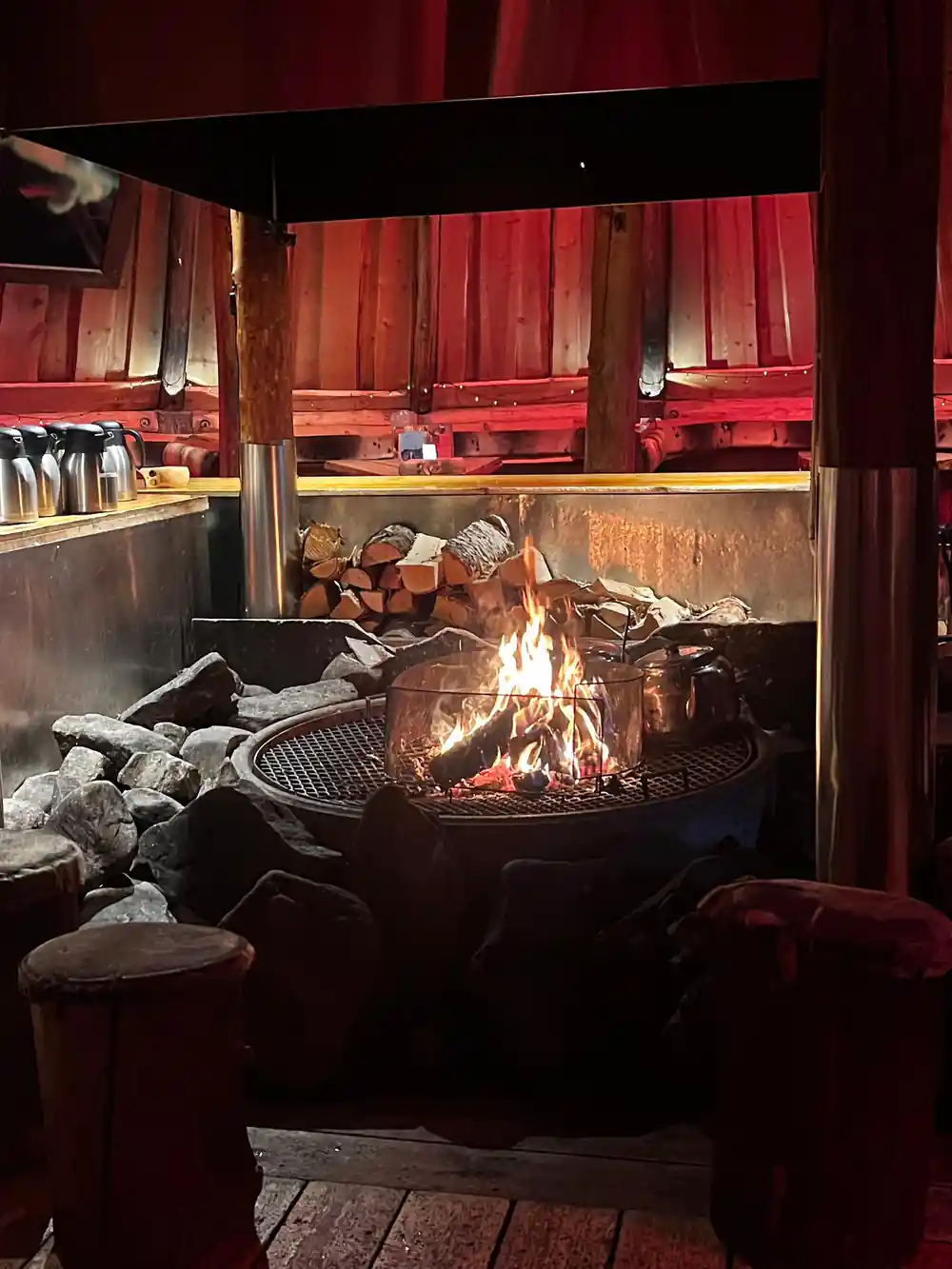 An open fire burning in the hearth of a red timber Gamme hut